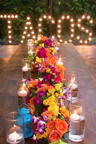wedding taco bar on a long table bright flowers and candles on the background inscription tacos with light bulbs bohemiadelmar