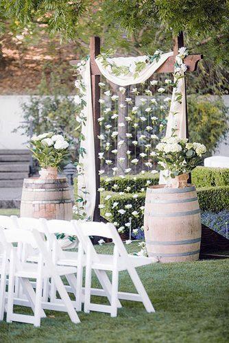 wine barrels an arch decorated with a white cloth and flowers surrounded by wine barrels with flowers clane gessel photography