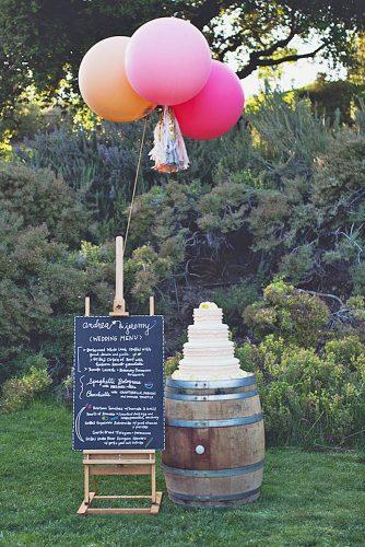 wine barrels on which stands a tall white cake sign with inscriptions decorated with balloons e p love