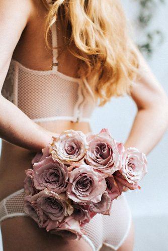 wedding boudoir book bride in white lingerie holds behind her pink flowers hazelwood photo