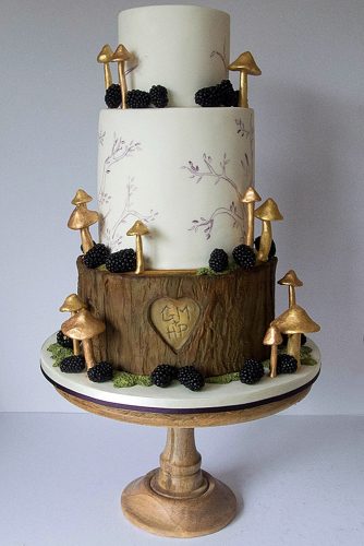 woodland themed wedding cakes three tiered cake with a wooden bottom layer of a heart with initials and golden mushrooms happy hills cakes