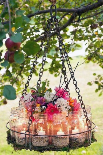 rustic backyard wedding decoration a chandelier suspended with a tree with candles in mason jars and flowers midwest living via instagram