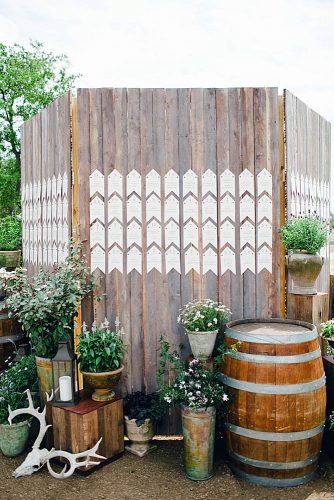 rustic backyard wedding decoration escort card display on a wooden fence flowers in barrels and buckets the nichols via instagram