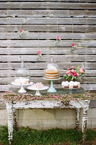 rustic backyard wedding decoration old dessert table decorated with flowers on a background of flowers in glass jars lauren fair photography