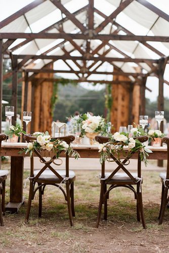 rustic backyard wedding decoration under a wooden awning table and chairs decorated with flowers and inscriptions bryan n miller photography