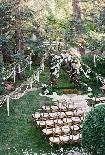 rustic backyard wedding decoration whitewashing ceremony with a lush arch of white flowers and ribbons jenna walker photography