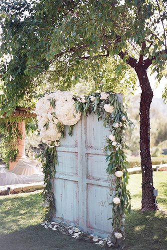 rustic backyard wedding decoration wooden old blue door backdrop decorated with green and white flowers clayton austin