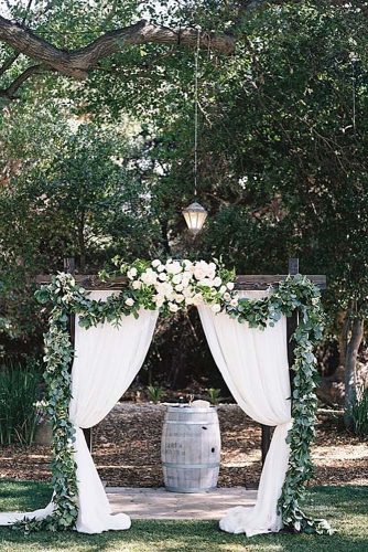 wine barrels a wedding arch made of wood decorated with cloth and greenery a wine barrel as an altar ashley kelemen photography via instagram