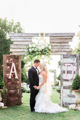 old door wedding decoration ideas the bride and groom hold hands on the background of wooden doors with monogram and white flowers aj dunlap via instagram