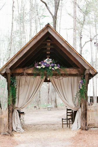western wedding decoration arch with a wooden triangular roof burlap curtains and flowers mark williams studio