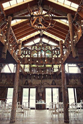 western wedding decoration ceremony in a barn with white chairs horns décor and stained glass windows megan hardre
