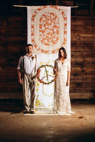 hippie wedding backdrop with fabrics in floral ornaments the bride and groom hold a flower peace wreath todd white photography