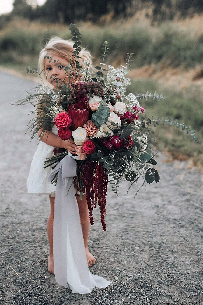 green wedding florals in the hands of a girl in a white lush bouquet with claret flowers and greens kat grabowski via instagram