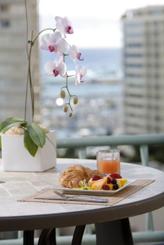 hawaii honeymoon breakfast with croissant and fruit on the hotel balcony ramadaplazawaikiki