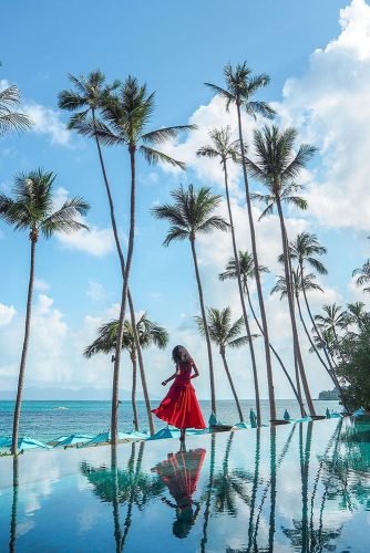 hawaii honeymoon girl in a red dress high palms the sky is reflected in the water thejoergensen