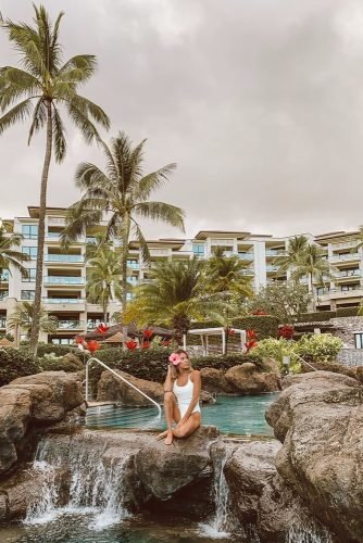 hawaii honeymoon girl in a white bathing suit with a flower in her hair by the pool hellofashionblog