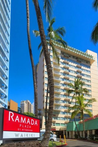 hawaii honeymoon sign at the entrance to the hotel tall building among palm trees ramadaplazawaikiki