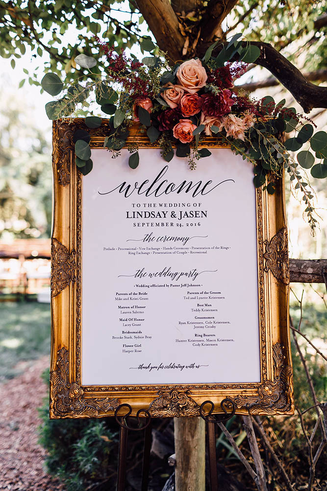 popular wedding signs in a golden frame decorated with flowers greeting inscription plum and oak