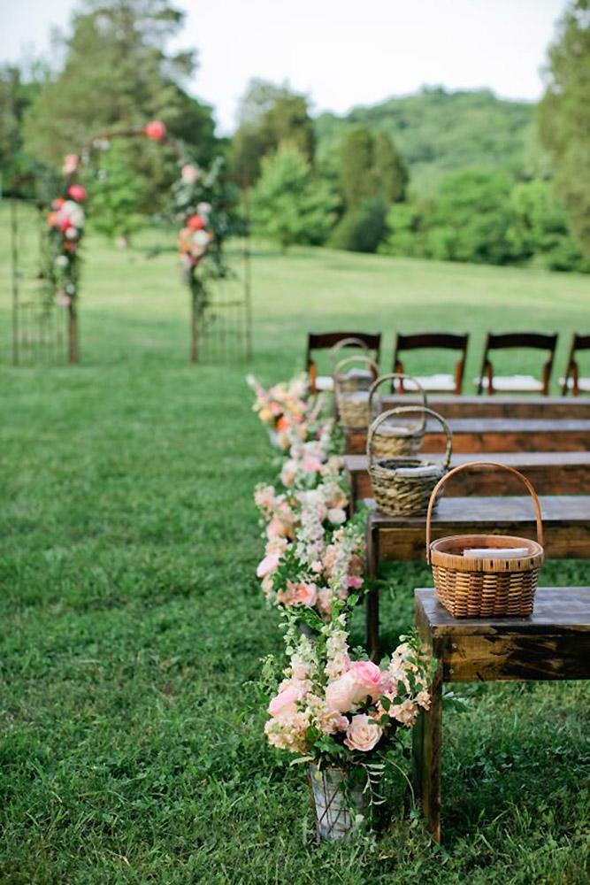 country wedding aisle decorated with flowers and wicker baskets kristyn hogan photography