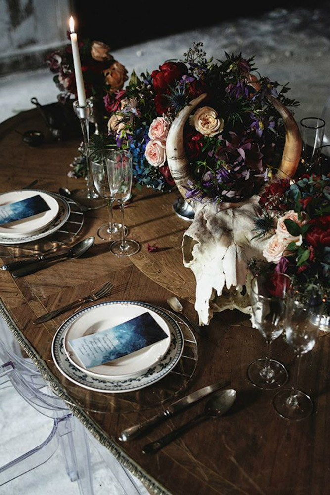 halloween wedding ideas a chic table with candles with dark flowers and a skull of a horned animal mikhail loskutov photography