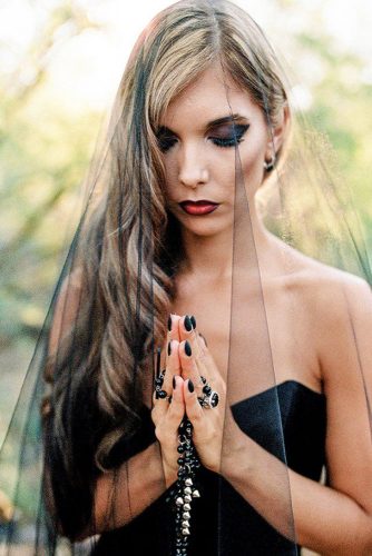 halloween wedding ideas bride in a black strapless dress with flowing hair bright make up and veil ashley rae