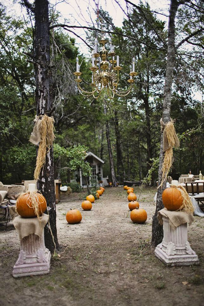 halloween wedding ideas wedding pass of orange pumpkins with a massive golden chandelier with candles rachael lindsy photography