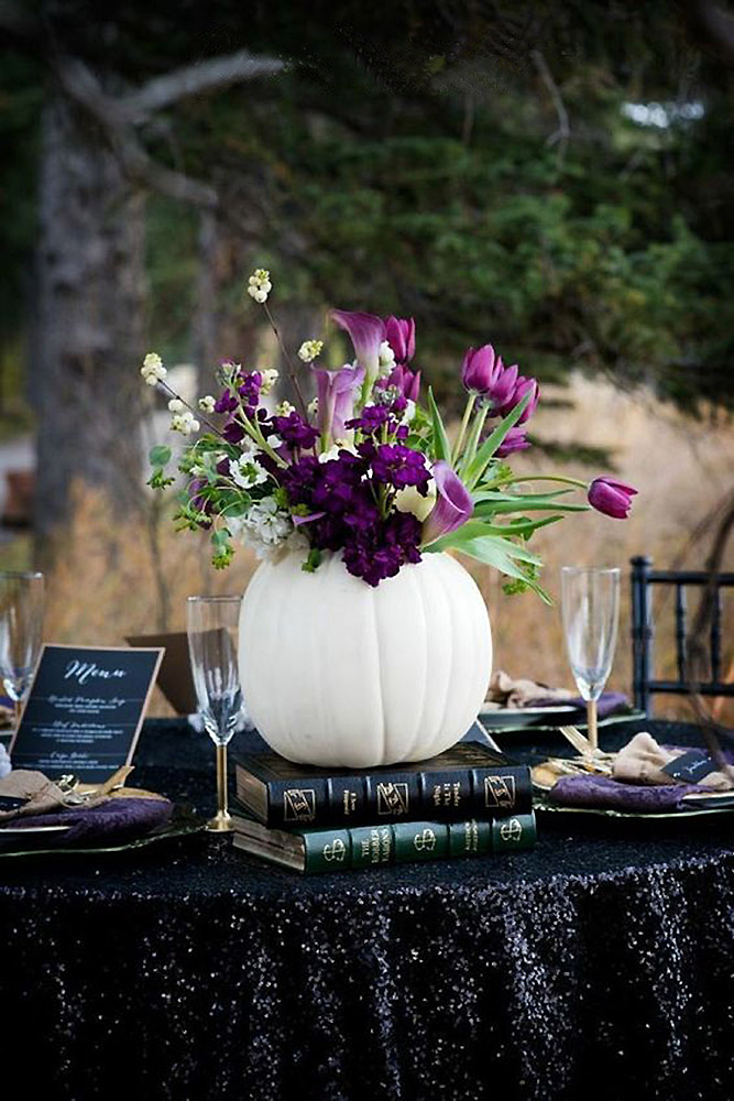 halloween wedding ideas white vase in the form of a pumpkin with purple flowers tulips and callas on a table covered in black christydswanbergphotography