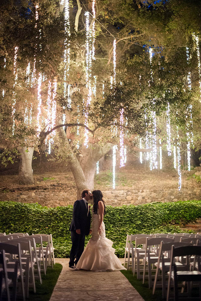 wedding light kiss of the bride and groom against the background of a tree decorated with cascade lights shewanders photography