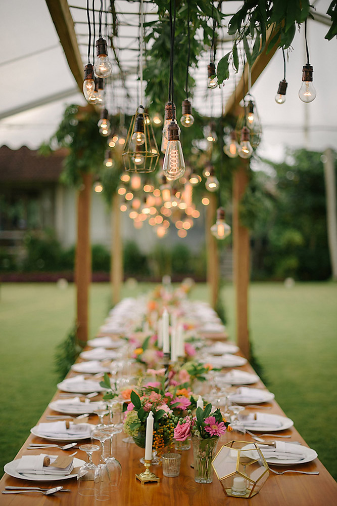 wedding light long decorated with flowers and candles over a table light bulb bali wedding photographer via instagram