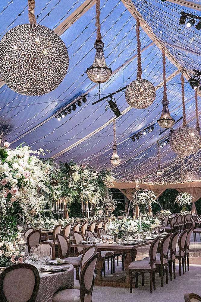 wedding light luxurious reception under a transparent awning with shiny chandeliers jessica claire via instagram