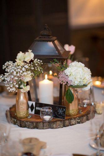 rustic wedding lanterns centerpiece with candle on wooden slice and gold bottles with glitter and flowers kathleen landwehrle photography