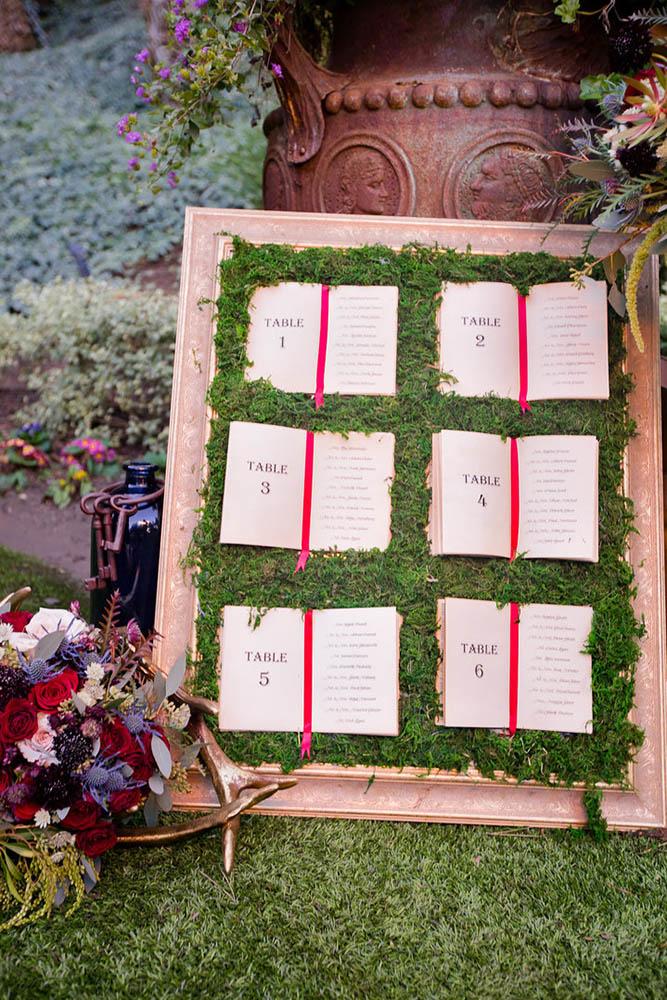 disney wedding table plan with moss and books from alise in wonderland raelyn elizabeth photography