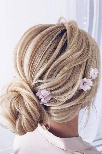 elstile wedding hairstyles textured low bun on blonde hair with pink flowers elstilespb