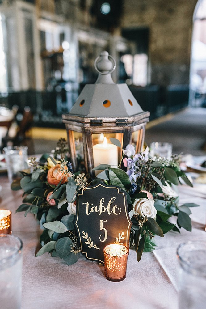 rustic wedding centerpieces candle lantern greenery and flowers mackensey alexander photographer