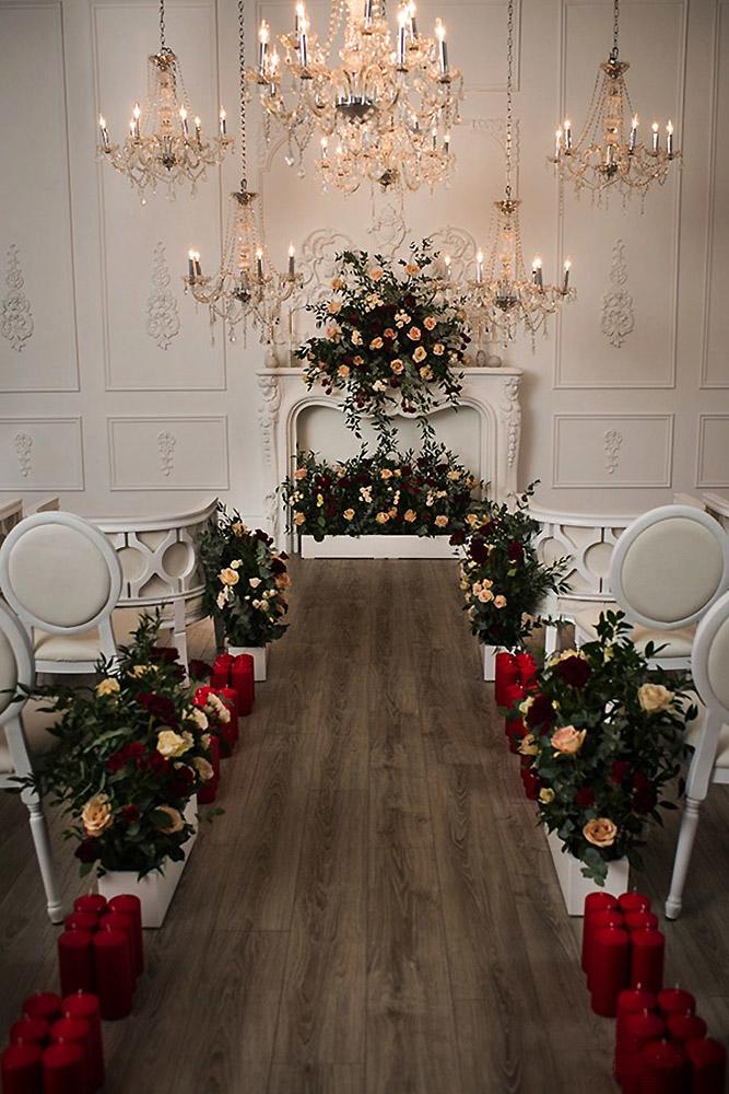 christmas wedding ceremony aisle with red candles flowers and greenery banga studios