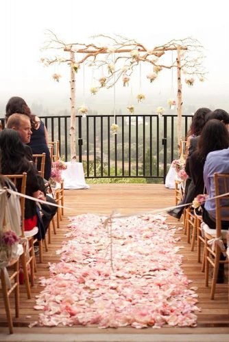 dusty rose wedding aisle with petals and arch with wooden branches and hanging flowers in jars julie mikos