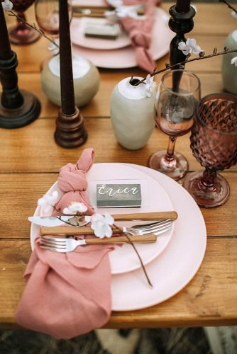 dusty rose wedding place setting with white flowers and napkin on wooden table from the daisies