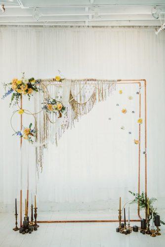 mustard wedding bohemian minimalistic arch with macrame flowers greenery and dark candkes brandi potter photography