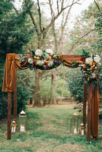 mustard wedding velvet cloth on wooden arch with flowers and greenery sean cook weddings