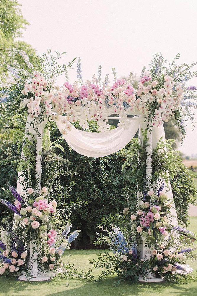 spring wedding decor outdoor ceremony altar with gentle spring blue lilac pink flowers white cascading orchids and cloth beigeweddings