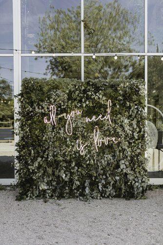 sage green wedding backdrop with romantic neon sign and greenery jenny demarco weddings
