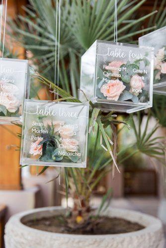 sage green wedding transparent cube with table setting signs greenery and roses inside maria sundin photography