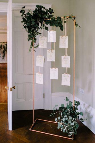 minimalist wedding decor metallic gold stand tableplan with greenery cluskey smith