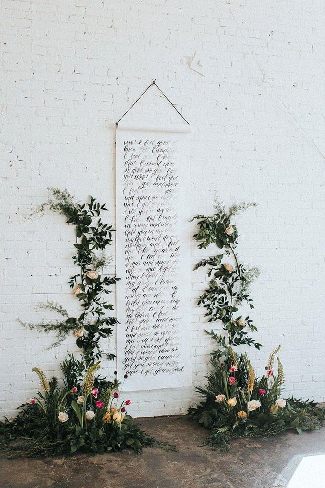 summer wedding trends ceremony backdrop with calligraphy signs and greenery and flowers jacobyphotoanddesign