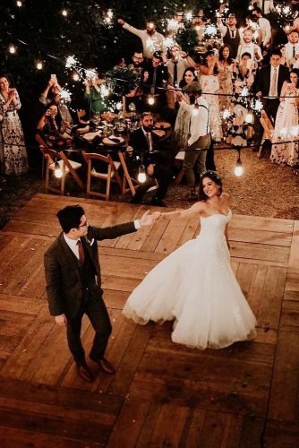 wedding party pictures the bride and groom dance on a wooden dance floor in the rustic style in the courtyard of the waters with glowing lights fernando caballero via ins