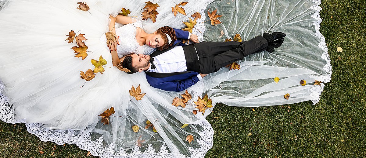 fall wedding party bride and groom together in the leaves featured