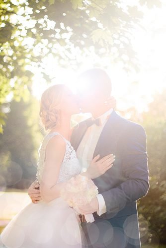 unique wedding ceremony script newlyweds kissing against the sun
