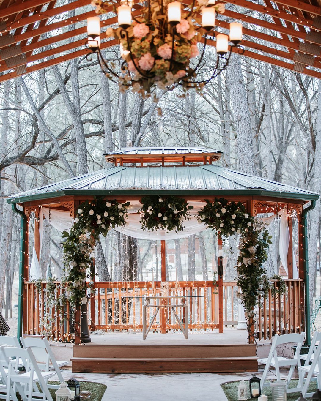 winter wedding decorations the ceremony in the gazebo is decorated with lanterns of greenery with white flowers and light fabrics emily joanne wedding films and photography