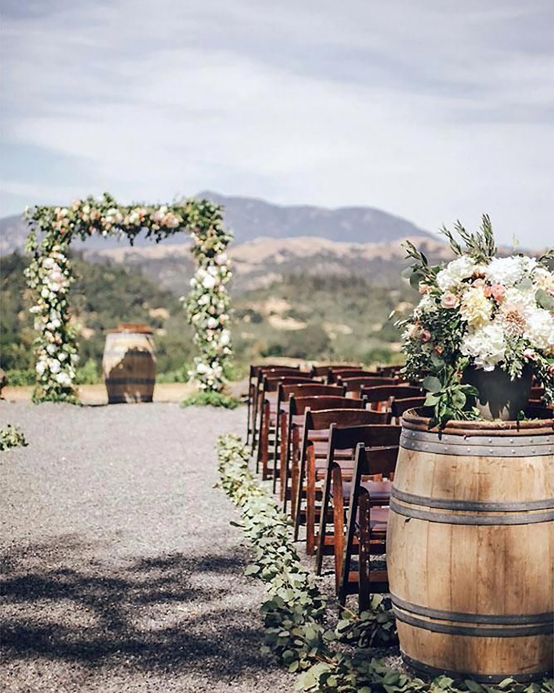 rustic wedding decor outdoor ceremony wine barrel flowers and greenery arch edyta szyszlo photography