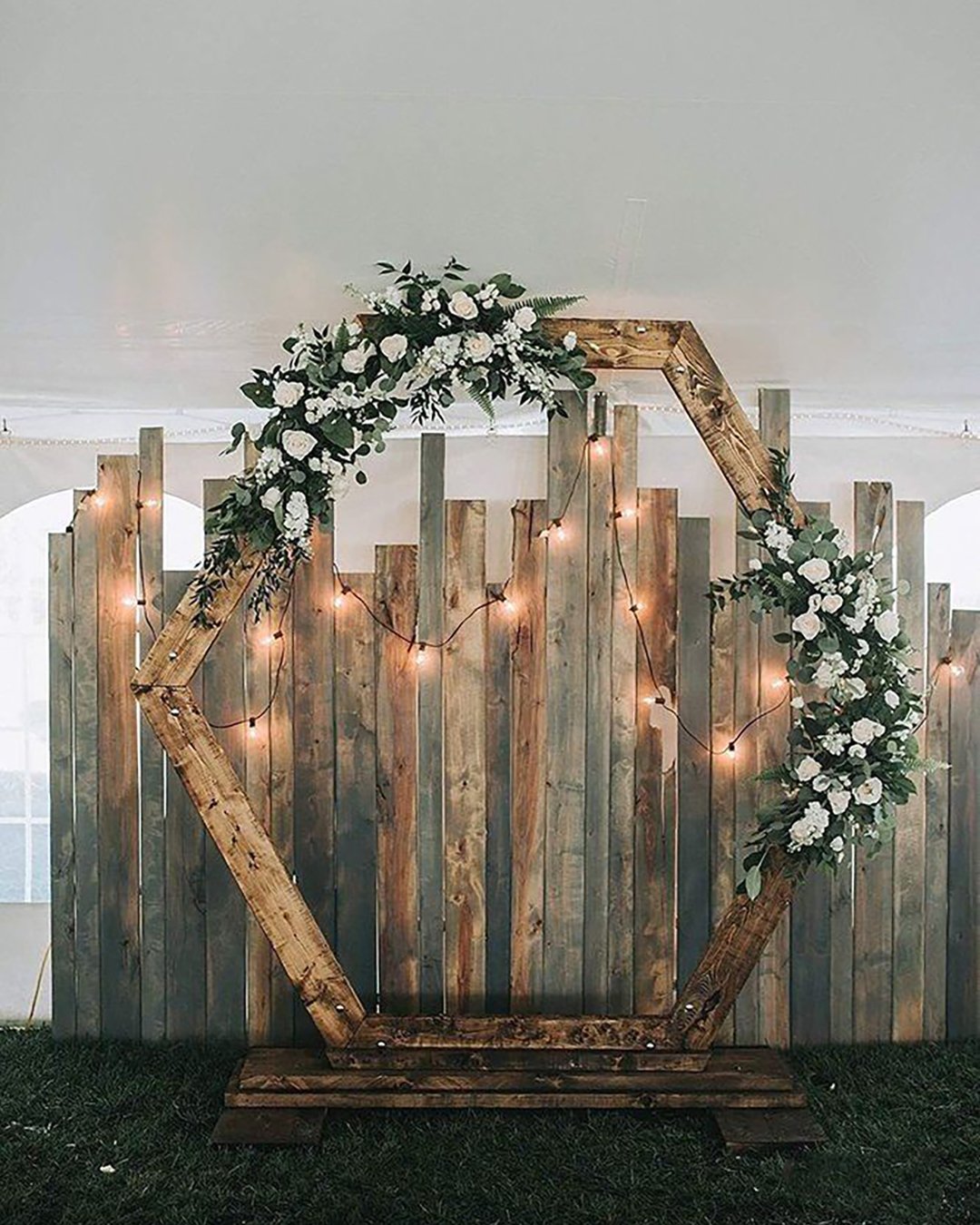 rustic wedding décor hexagon shaped backdrop with greenery and roses and lightbulb dorothy renzi